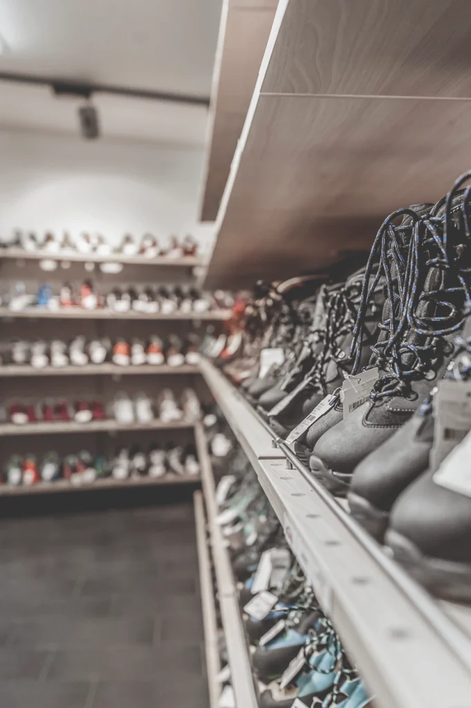 Reihen von Schuhen in den Regalen eines Schuhgeschäfts, vor allem Stiefel mit blauen Schnürsenkeln.