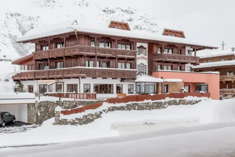 Hotel Garni Pirchhütt: Ein großes Hotel im Chalet-Stil, umgeben von Schnee in einer Berglandschaft.