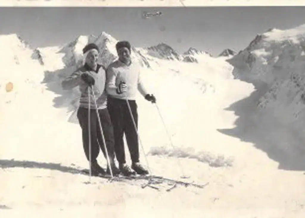 Zwei Personen auf Skiern genießen die verschneiten Berge, die an die Geschichte der Familie Riml erinnern.