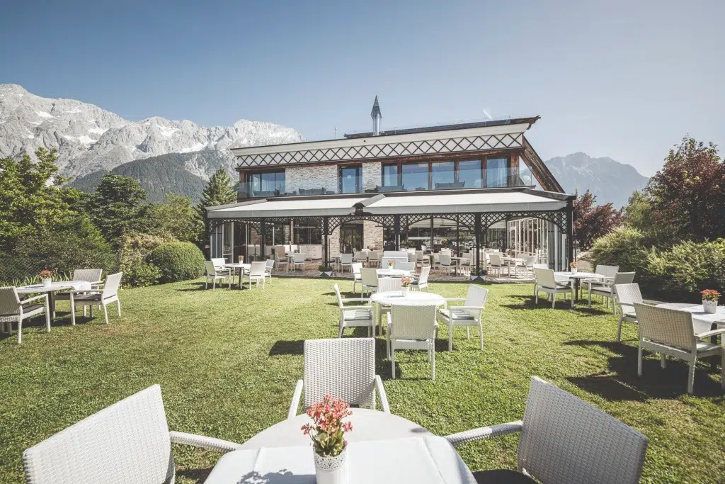 Weiße Terrassentische und Stühle auf einer Wiese, perfekt für die Heiraten Stöttlalm mit Bergblick.