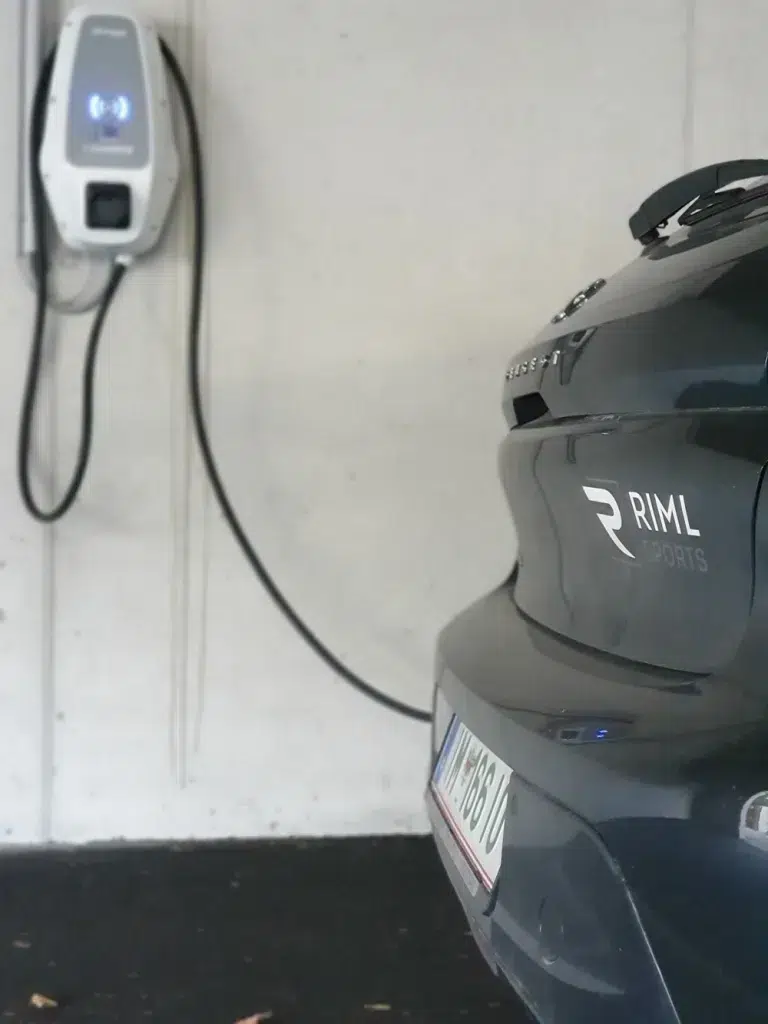 Aufladen von Elektroautos an einer Wandtankstelle, die den Grundsätzen der Nachhaltigkeit im Sporthandel entspricht.