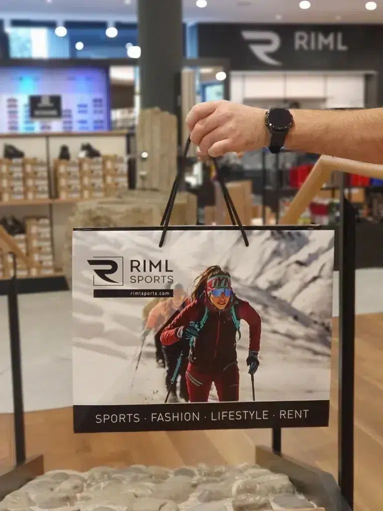 Die Hand hält eine RIML-Sporttasche, die im Geschäft auf Nachhaltigkeit im Sporthandel hinweist.