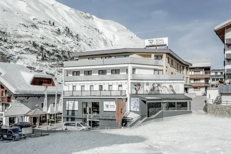 Ein modernes Gebäude der Piccard No5 Appartements mit großen Fenstern in einem verschneiten Bergdorf.