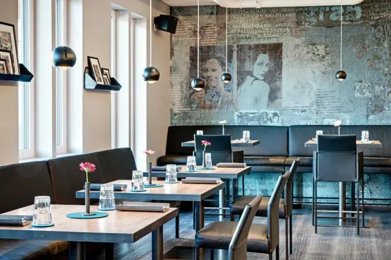 Föger's Restaurant ist mit schwarzen Sitzmöbeln, Holztischen und Wandkunst mit monochromen Gesichtern ausgestattet.