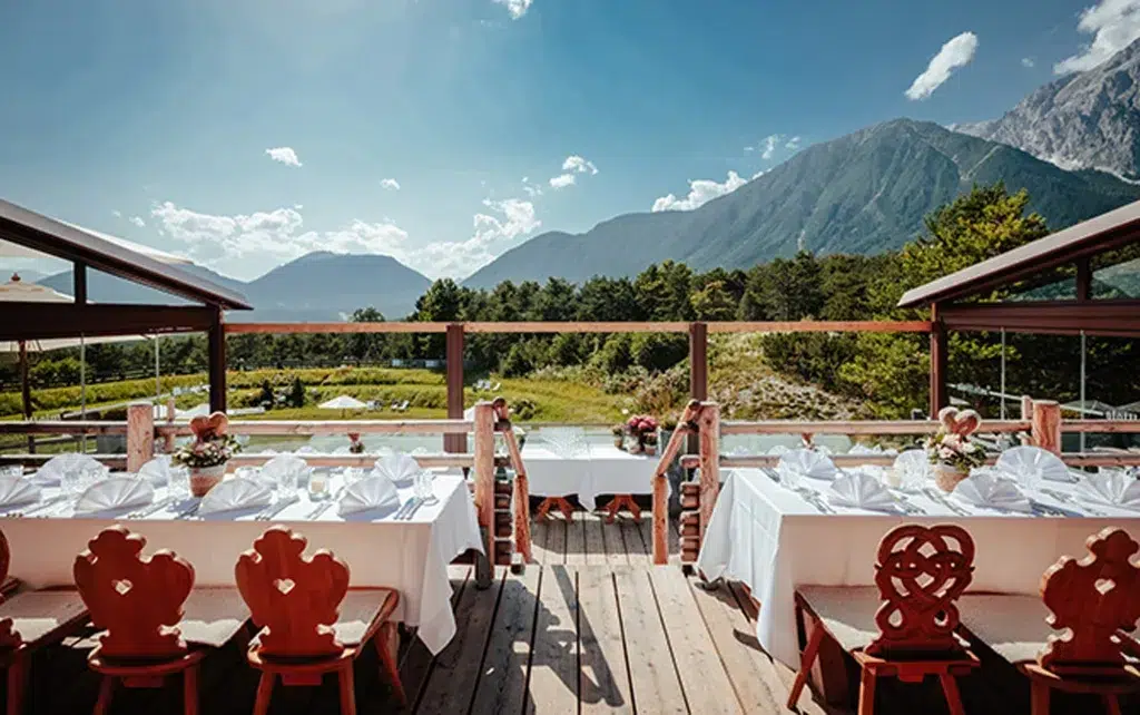 Außenrestaurant mit gedeckten Tischen für die Heiraten Stöttlalm mit Blick auf Berge und Grün.