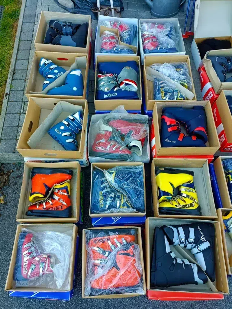 Kisten mit bunten Skischuhen, perfekt für jeden Skiinfluencer, fein säuberlich angeordnet auf einem Outdoor-Markt.