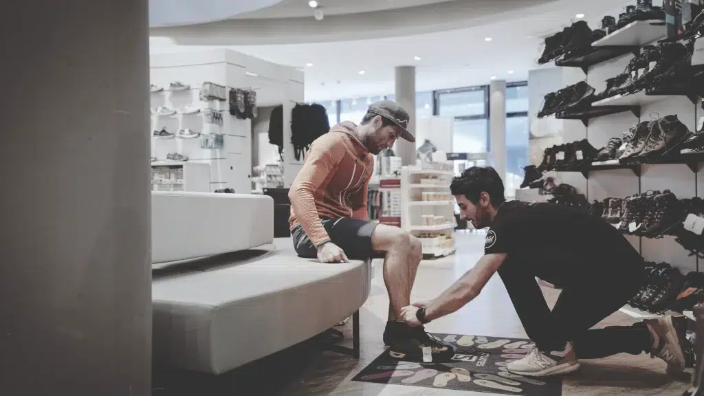Ein Angestellter hilft einem Mann beim Anprobieren von Schuhen in einem modernen Schuhgeschäft.