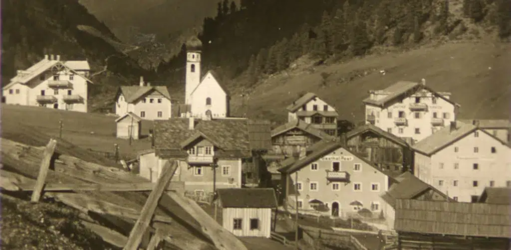 Altes Foto eines Alpendorfs, das die Geschichte der Familie Riml und das Erbe der Berge widerspiegelt.