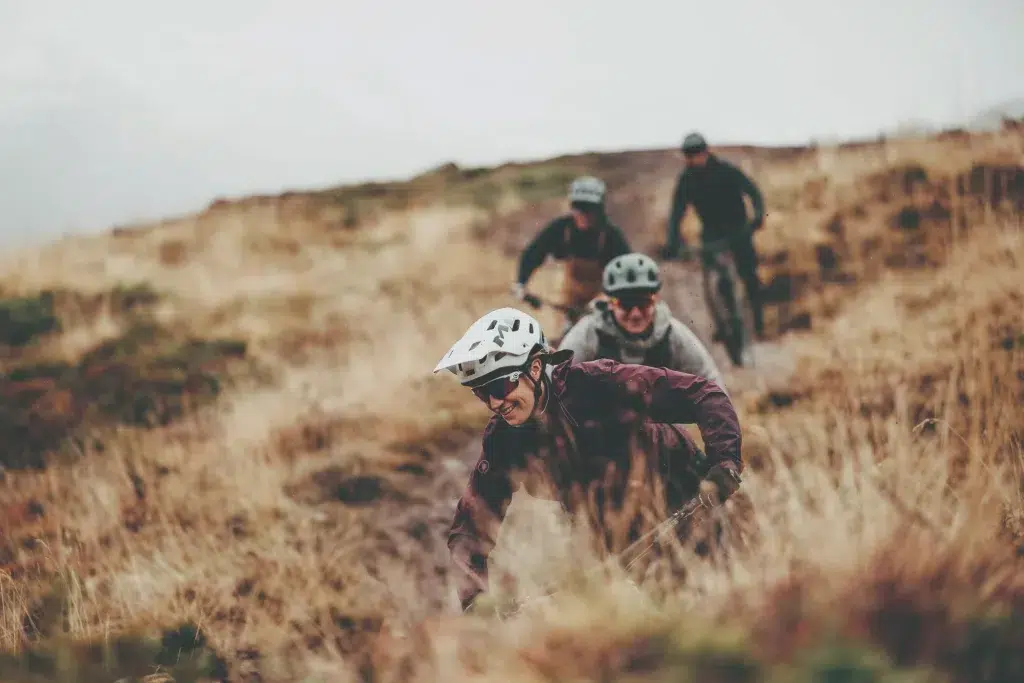 Vier Radfahrer fahren mit gemieteten Mountainbikes auf einem grasbewachsenen, unbefestigten Weg im Freien.