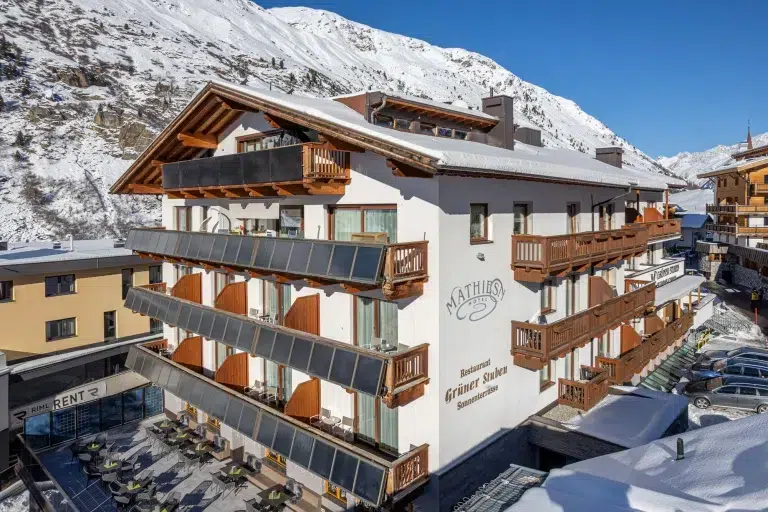 Hotel Mathiesn: Ein schneebedecktes Alpenhotel mit Holzbalkonen und verschneiter Berglandschaft.