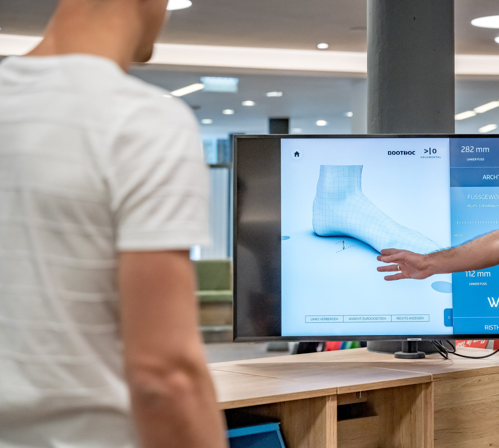 Zwei Männer besprechen einen 3D-Fußscan für Sicherheit am Berg in einem modernen Büro.