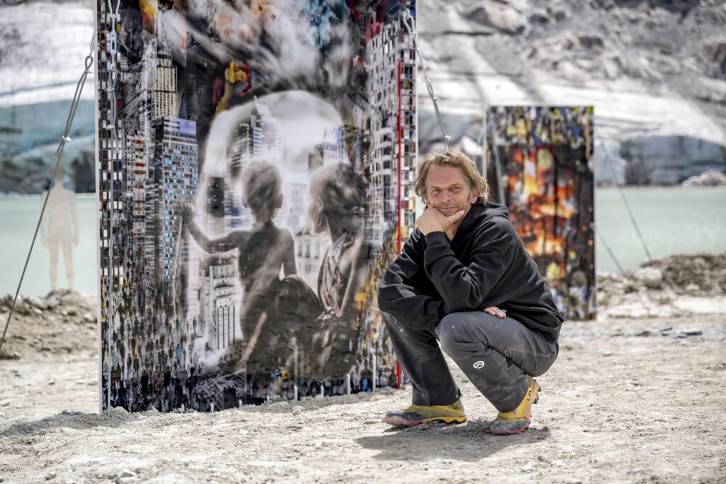 Ein Mann hockt im Freien vor bunten Kunsttafeln und denkt über die Familie Riml Geschichte nach.