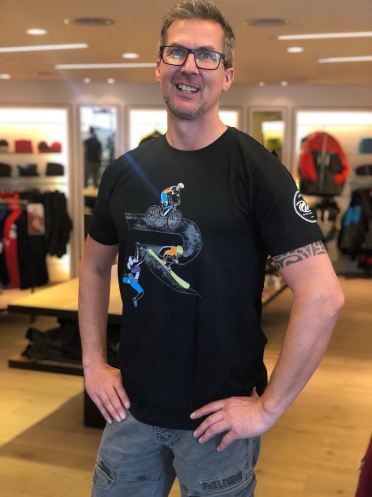 Lächelnder Mann in einem Skitest-Grafik-T-Shirt, der in einem Bekleidungsgeschäft steht.