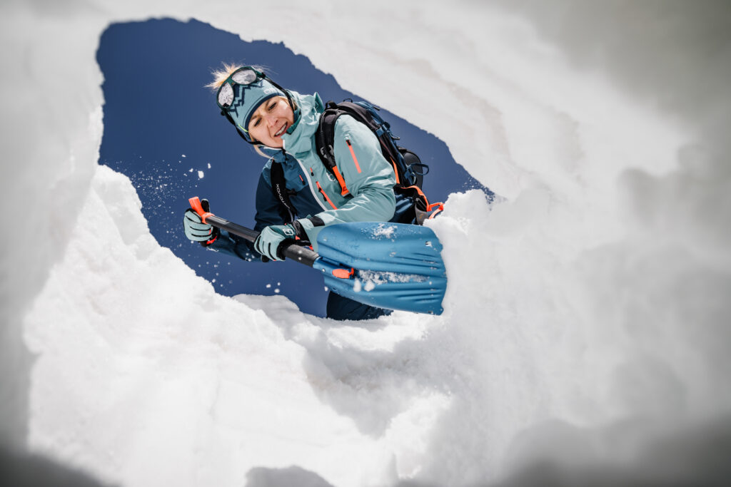 Ein Mitglied der menschlichen Ethnie schaufelt Schnee, gesehen aus einem verschneiten Tunnel heraus.