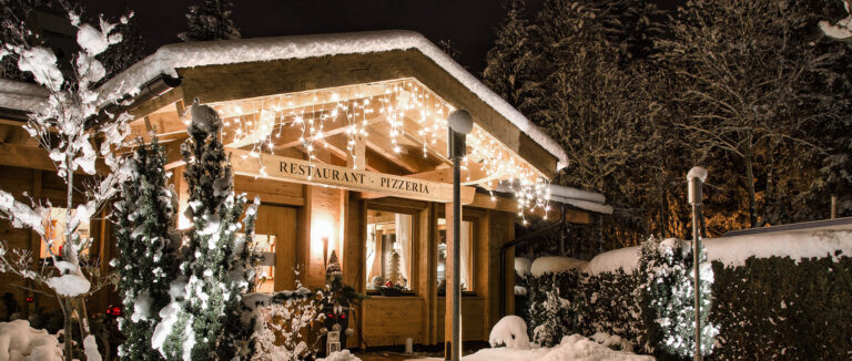 Föger's Restaurant: Ein gemütlicher Ort mit verschneitem Dach und festlicher Beleuchtung in einer Winternacht.