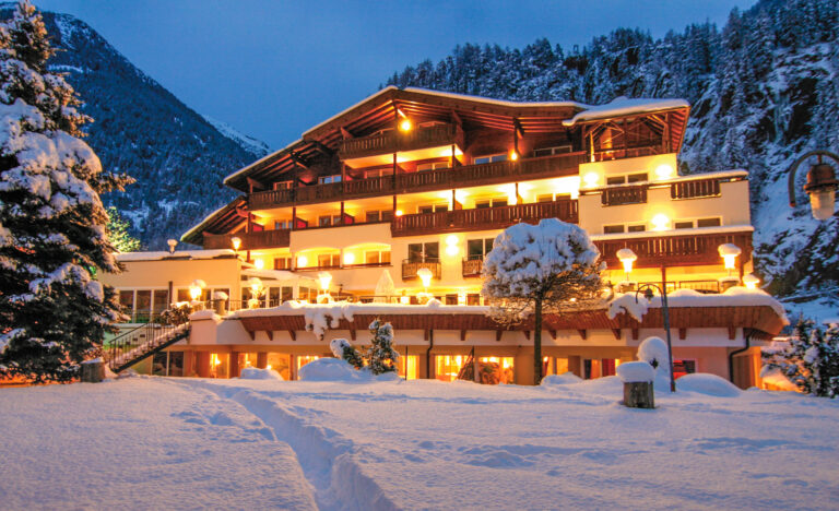 Hotel Mathiesn: Ein gemütliches, hell erleuchtetes Hotel inmitten einer verschneiten Winterberglandschaft.